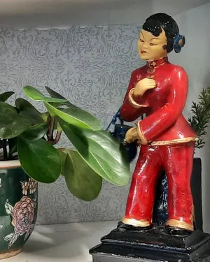 Painted figurine beside a houseplant